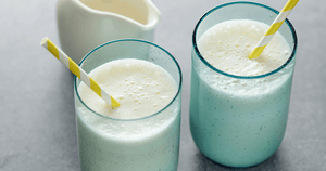 A high calorie drink served in two cups with straws